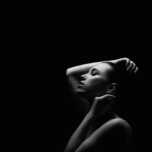NATIVE EXTRACTS: A mono image of a woman against a black background, light illuminating her skin.
