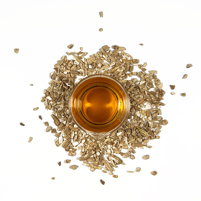Ashwagnadha Cellular Extract in a beaker surrounded by Withania somnifera dried root chips
