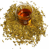 Barberry bark chips (Berberis vulgaris) surrounds a beaker with Barberry Bark Cellular Extract, golden orange in colour