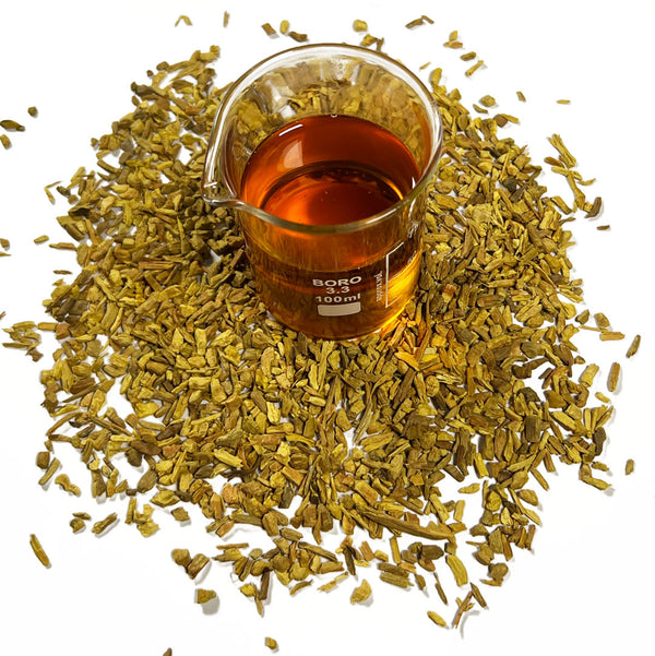 Barberry bark chips (Berberis vulgaris) surrounds a beaker with Barberry Bark Cellular Extract, golden orange in colour