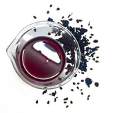 Deep dried purple grapes surround NATIVE EXTRACTS Grape Cellular Extract deep red in colour in a beaker